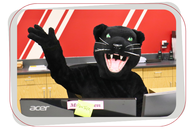 panther mascot sitting at desk and waving